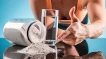 Female bodybuilder pointing to a pile of creatine